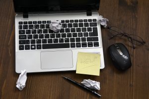 Laptop mit zerknitterten Papier und einem Post-IT HELP